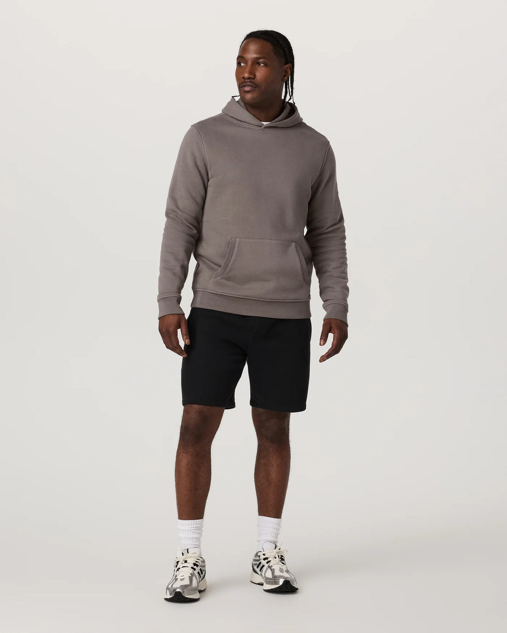 Man wearing a gray hoodie and black shorts on a white background