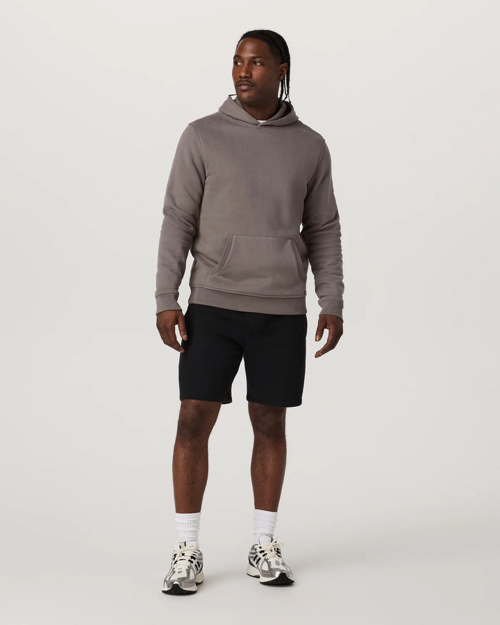 Man wearing a gray hoodie and black shorts on a white background