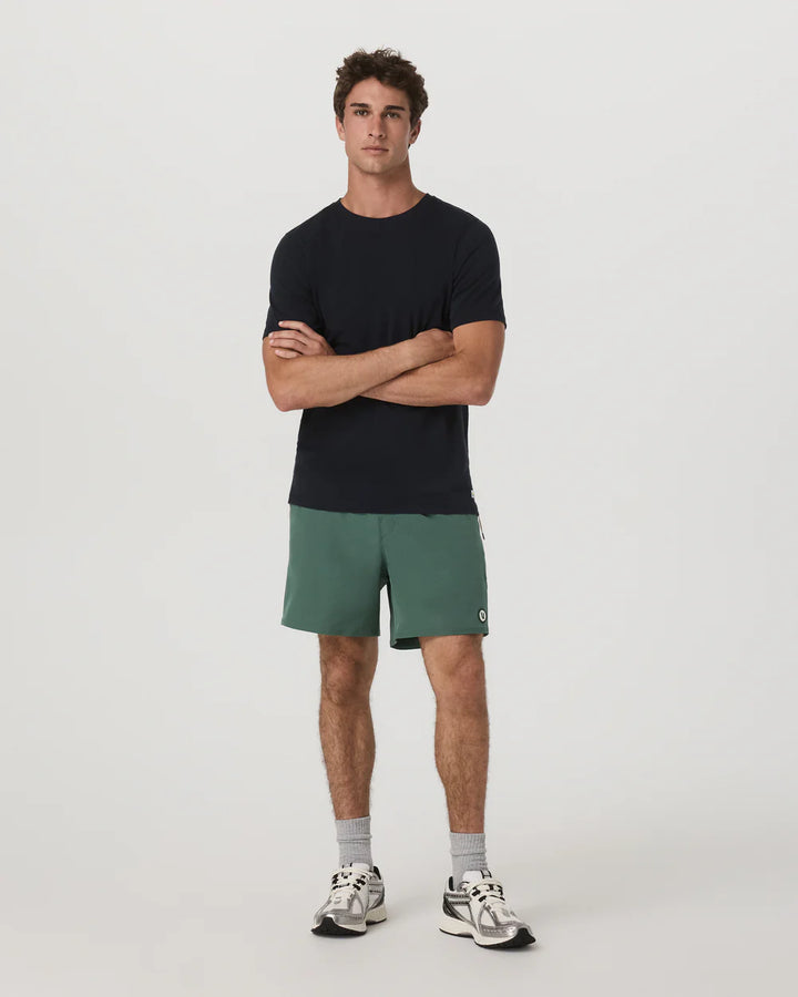 Man wearing a black t-shirt and green shorts on a white background