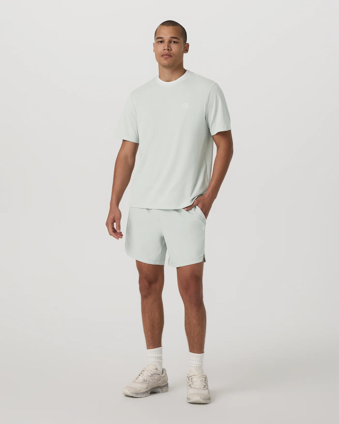 Man wearing a light green t-shirt and shorts set on a white background