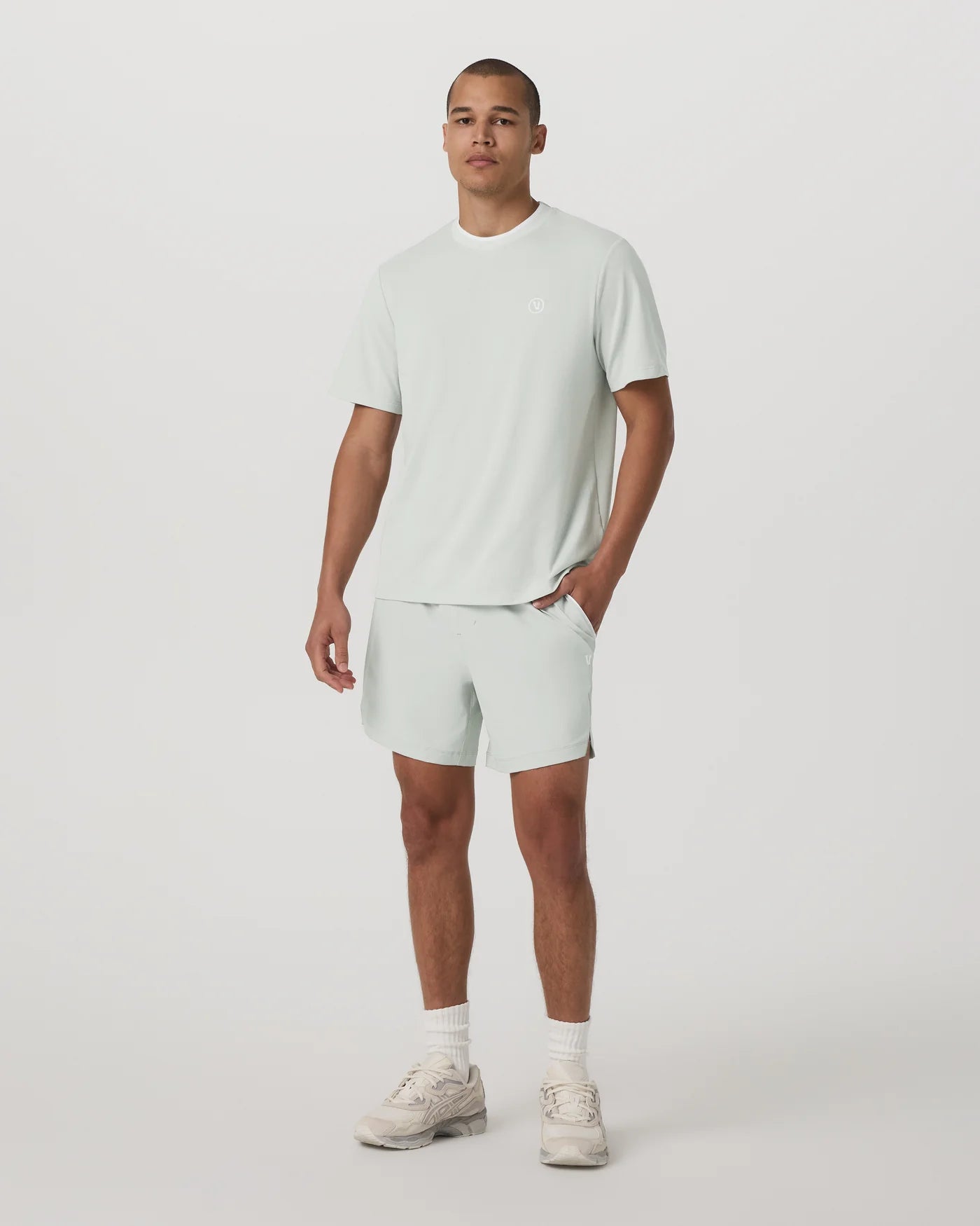 Man wearing a light green t-shirt and shorts set on a white background