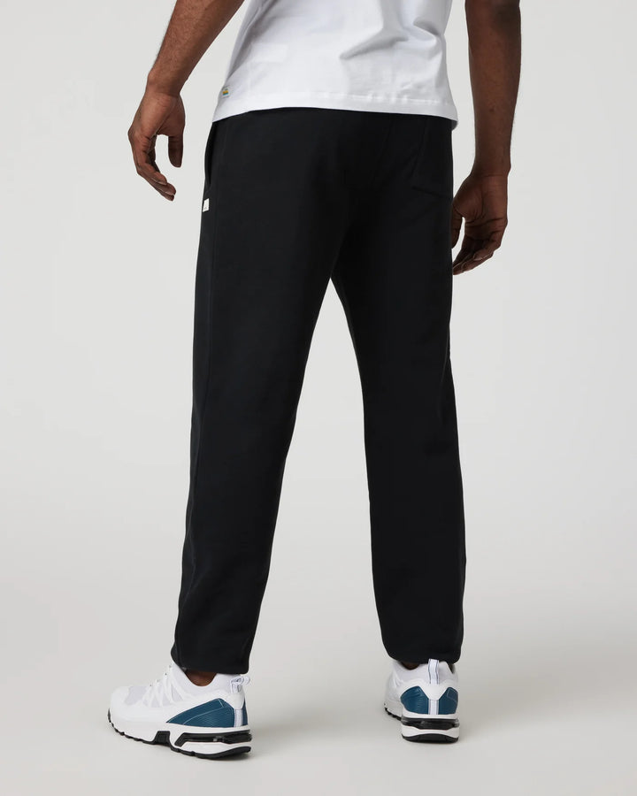 Person wearing black pants and white sneakers on a plain background