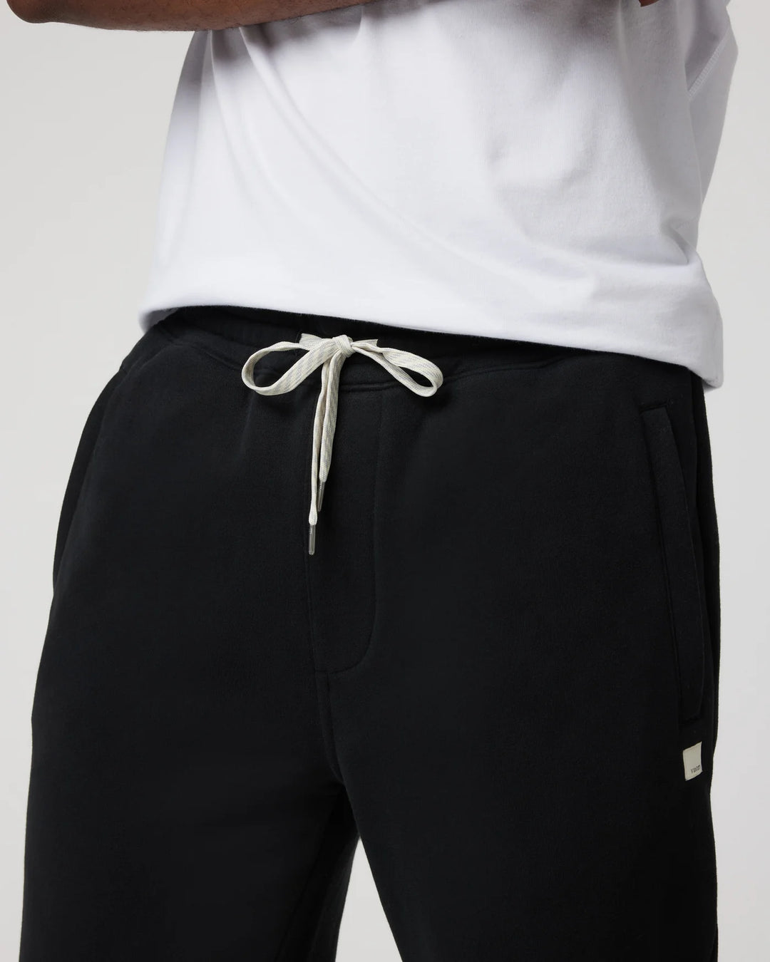 Person wearing black pants with a white drawstring and a small logo on a light gray background