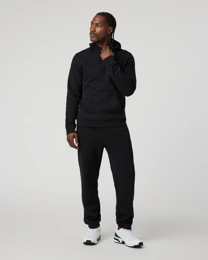 Man wearing a black tracksuit with white sneakers on a light gray background