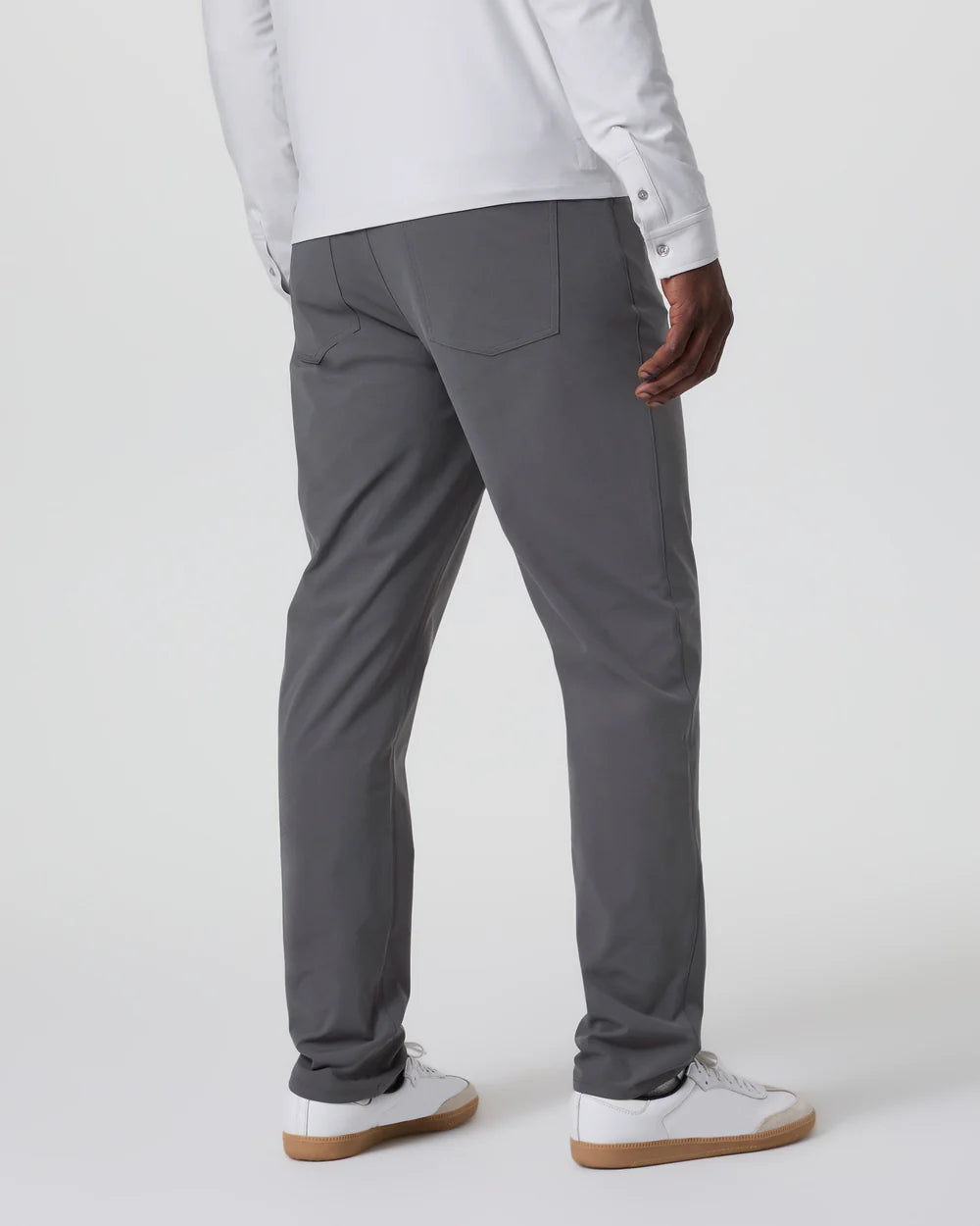 Person wearing gray pants and a white shirt on a plain background
