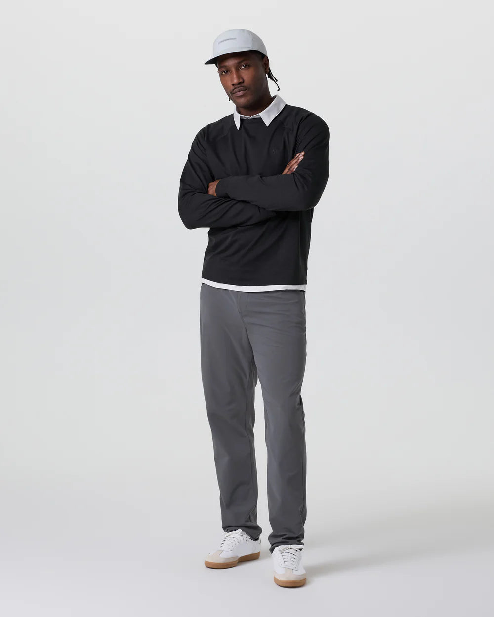 Man wearing a black sweater, gray pants, and white sneakers on a white background