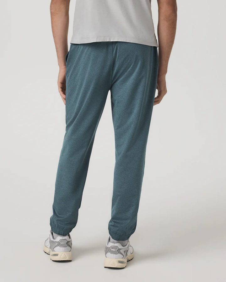 Person wearing teal jogger pants and white sneakers on a plain background