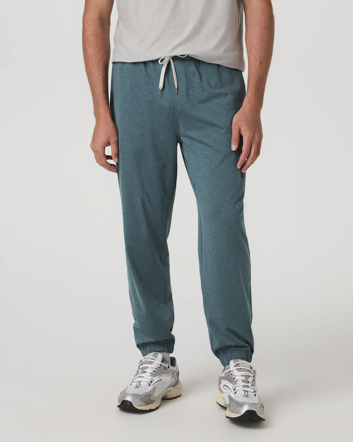 Person wearing teal jogger pants and white sneakers on a light gray background