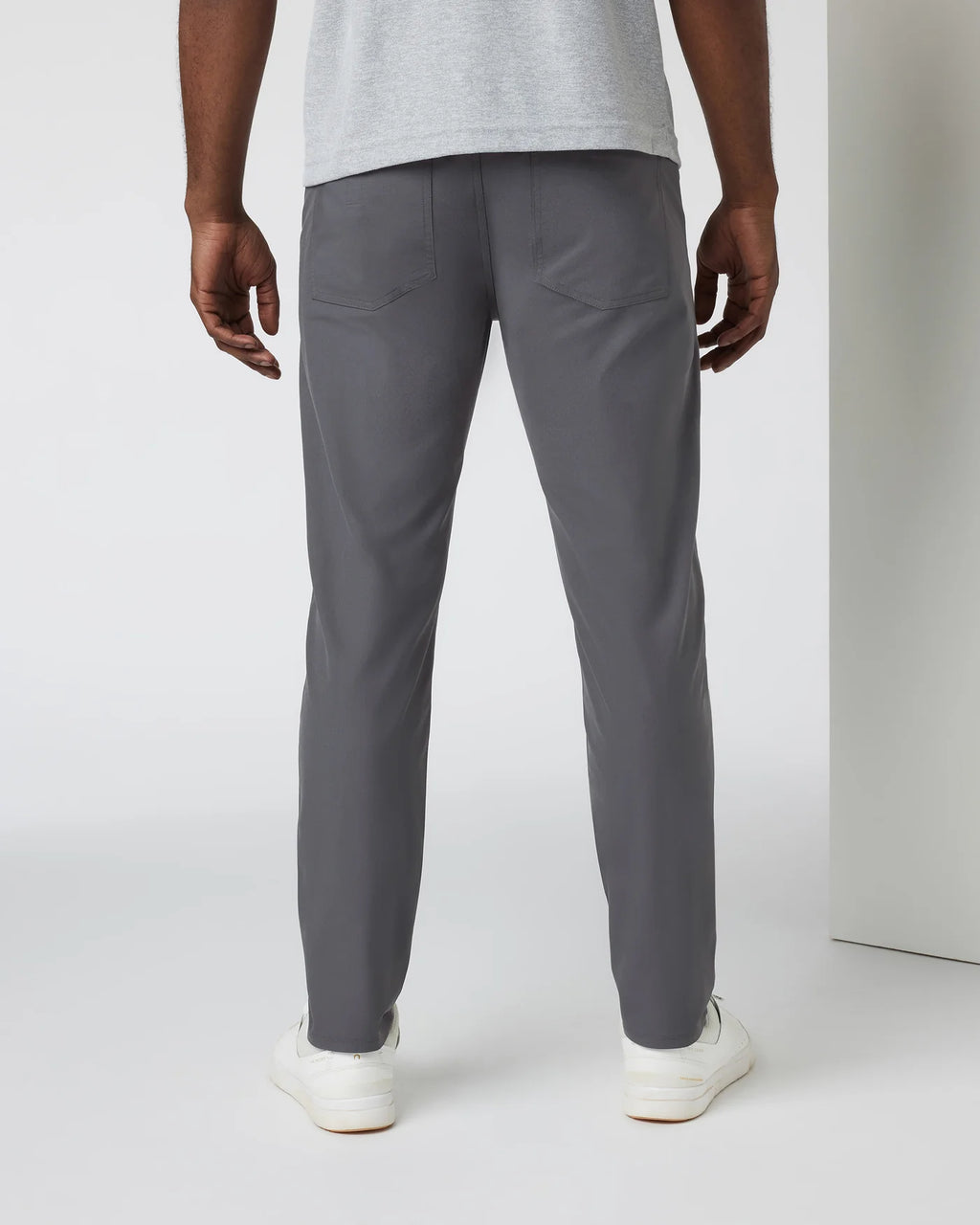 Person wearing gray pants and a light gray shirt on a white background