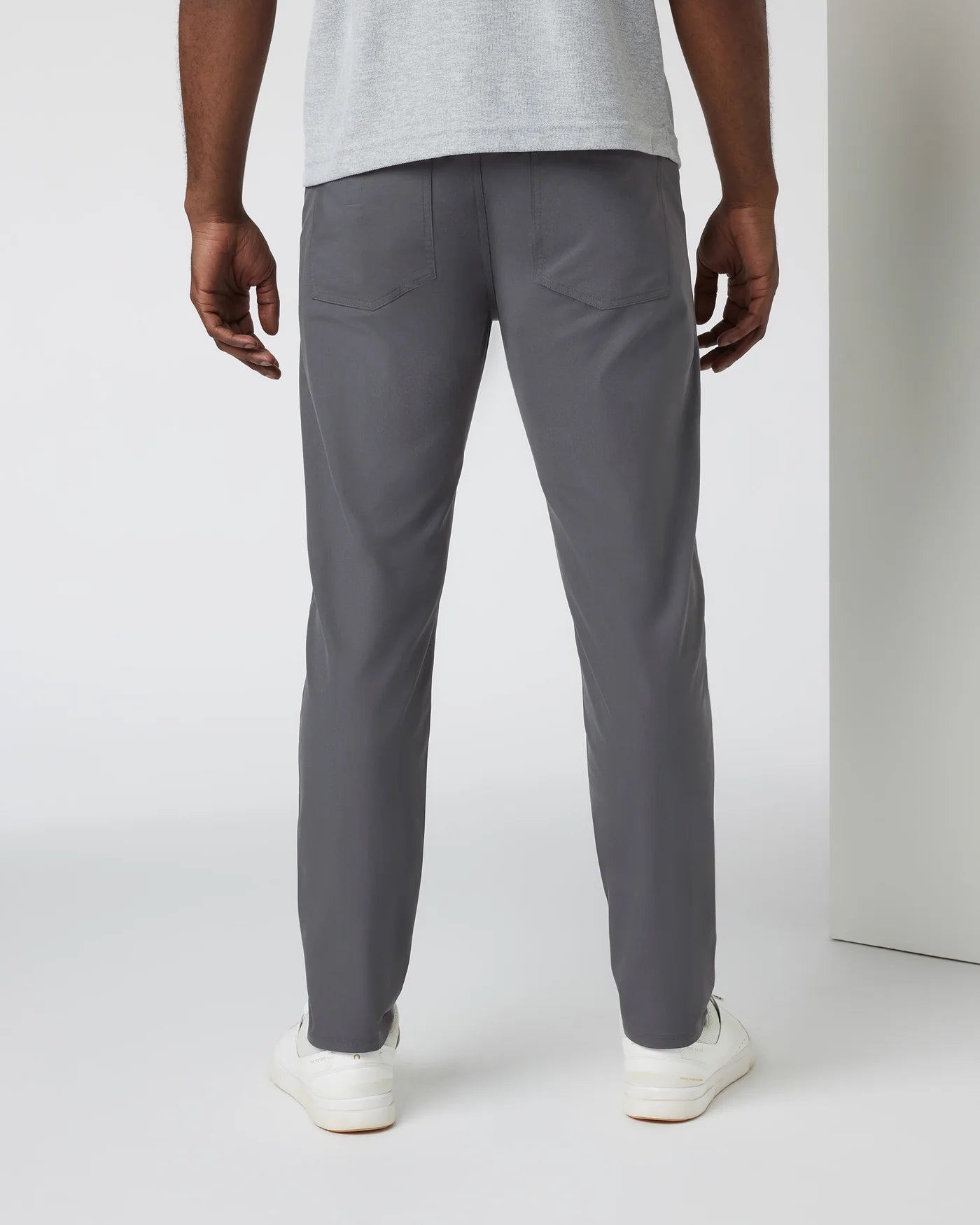 Person wearing gray pants and a light gray shirt on a white background