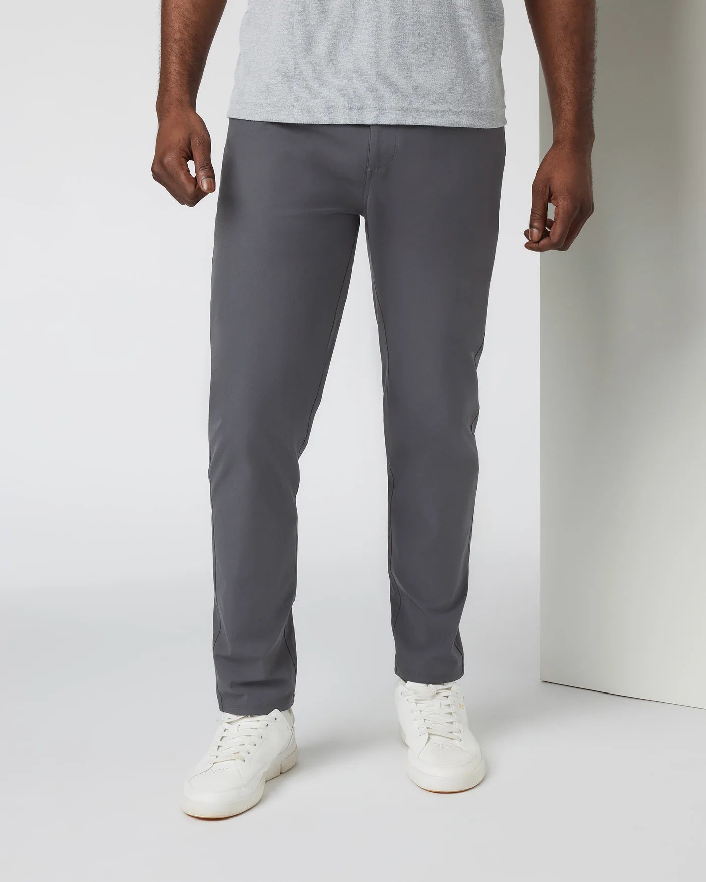 Person wearing gray pants and white shoes on a plain background