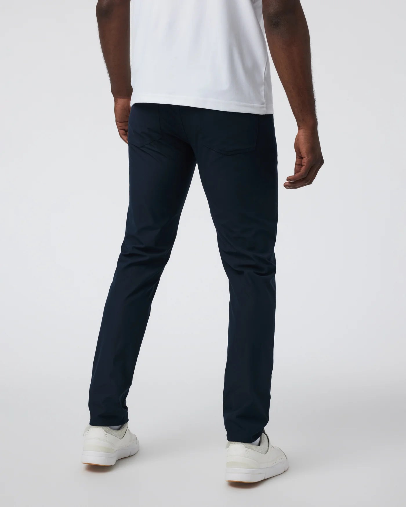 Person wearing navy pants and white shoes on a white background