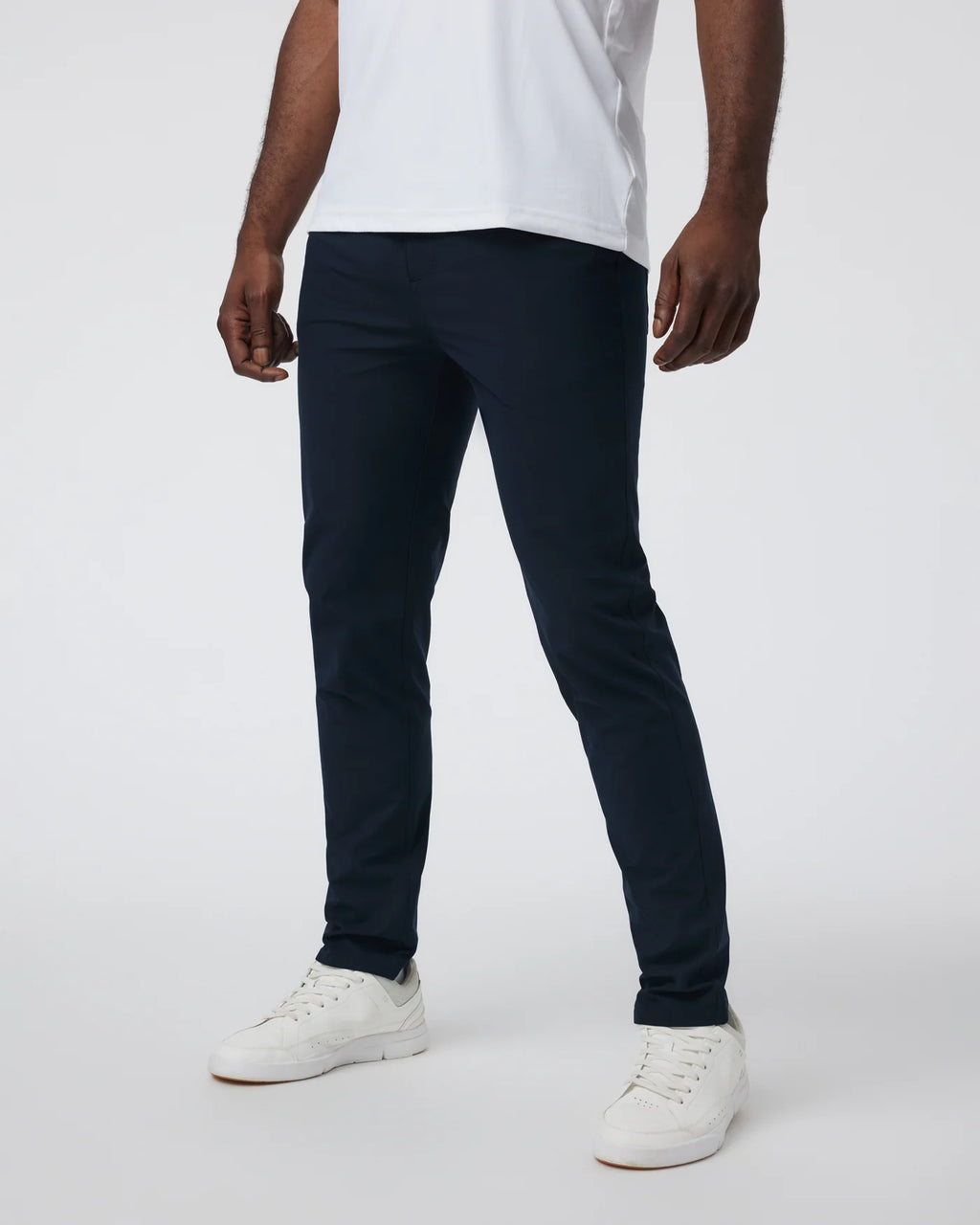 Person wearing navy pants and white sneakers on a white background