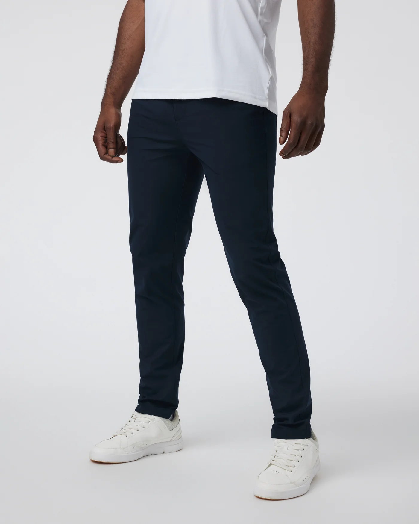 Person wearing navy pants and white sneakers on a white background