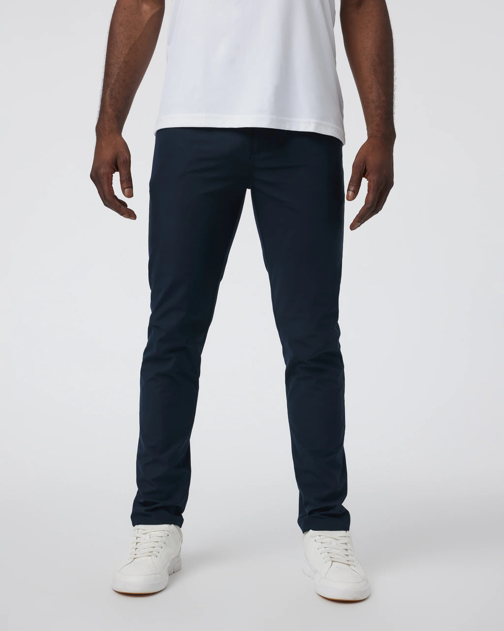 Person wearing navy pants and white shoes on a plain background
