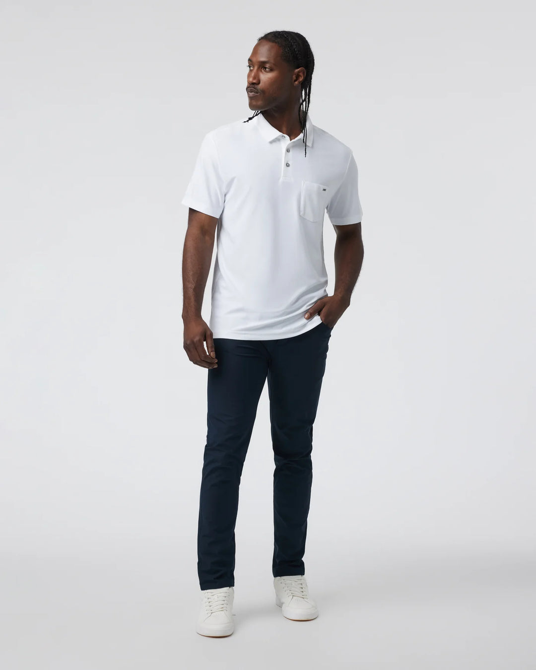 Man wearing a white polo shirt and dark pants on a white background