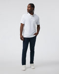 Man wearing a white polo shirt and dark pants on a white background