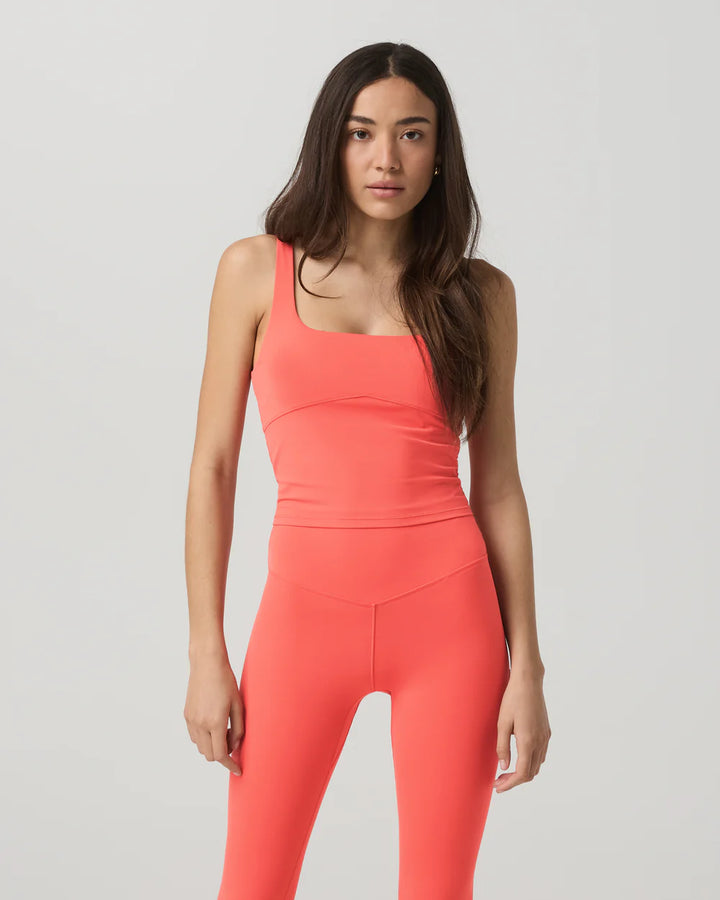 Woman wearing a coral pink jumpsuit on a light gray background