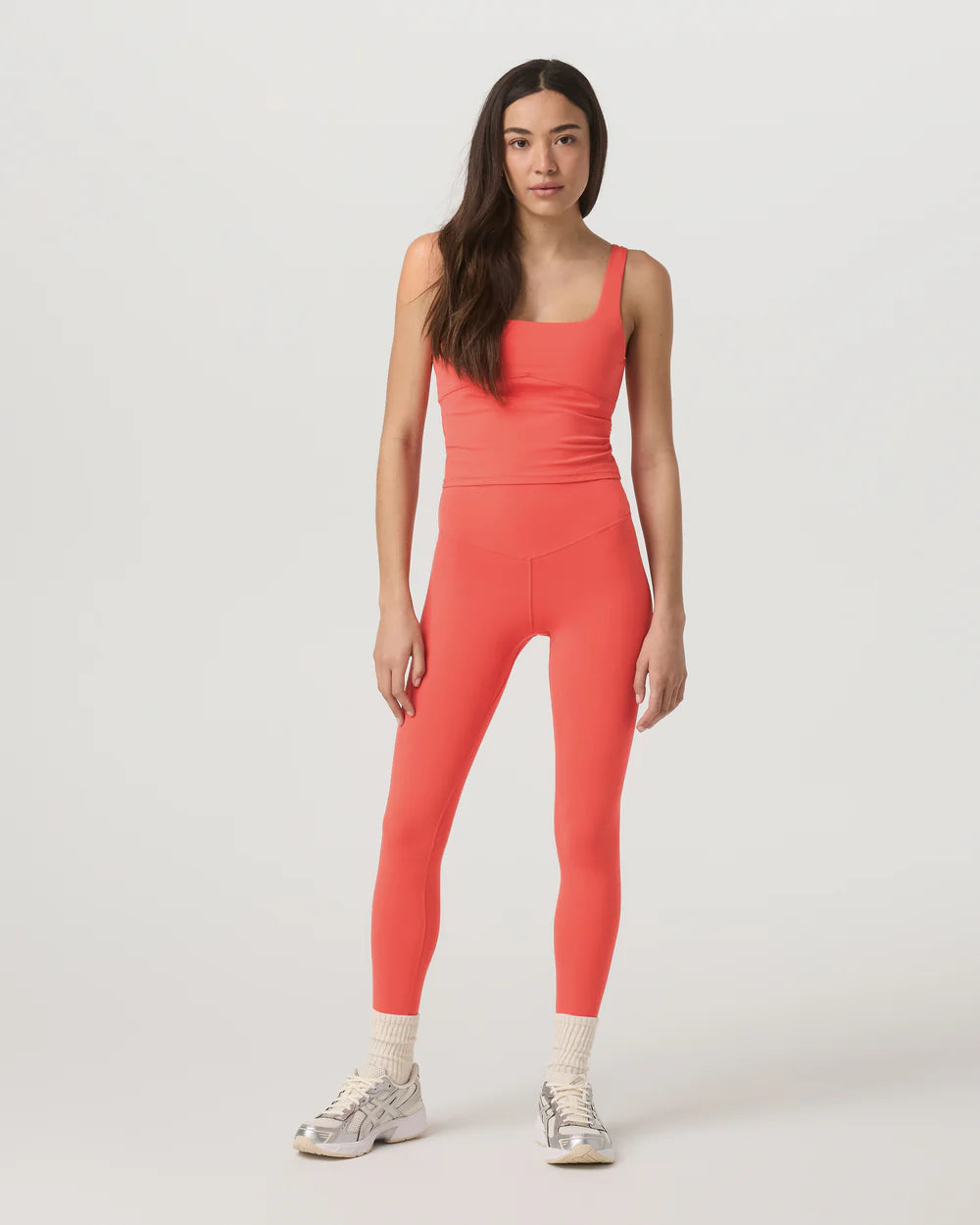 Woman wearing a coral jumpsuit on a white background