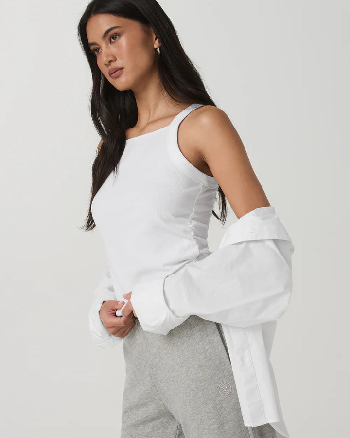 Woman wearing a white blouse with ruched details on a plain background