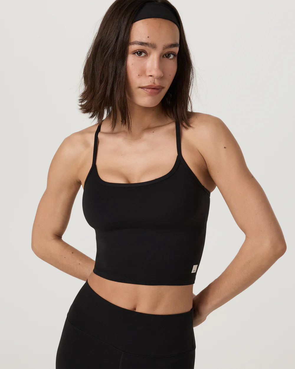 Woman wearing a black sports bra and leggings on a plain background