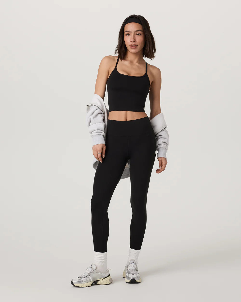 Woman wearing black athletic leggings and top on a white background