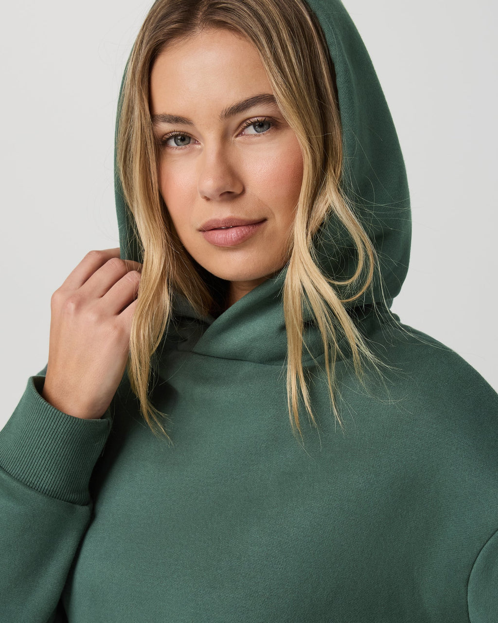 Woman wearing a green hoodie against a plain background