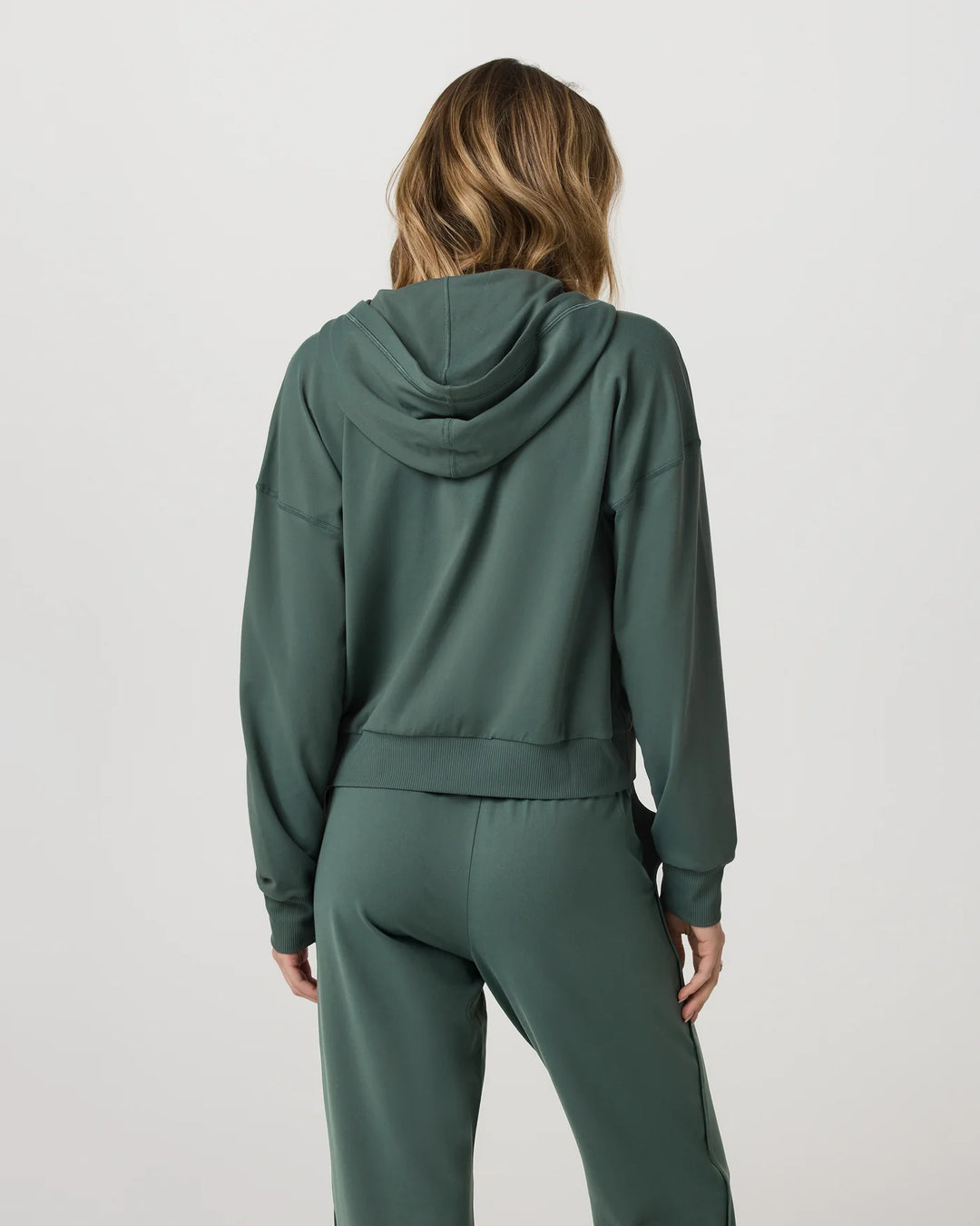 Person wearing a green tracksuit on a light gray background