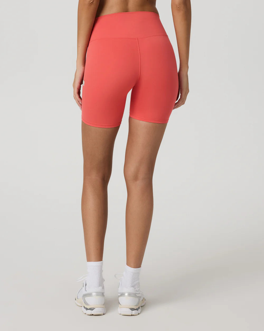 Person wearing coral pink high-waisted shorts on a white background