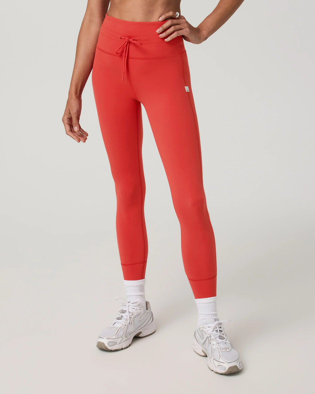 Person wearing red leggings and white sneakers on a light gray background