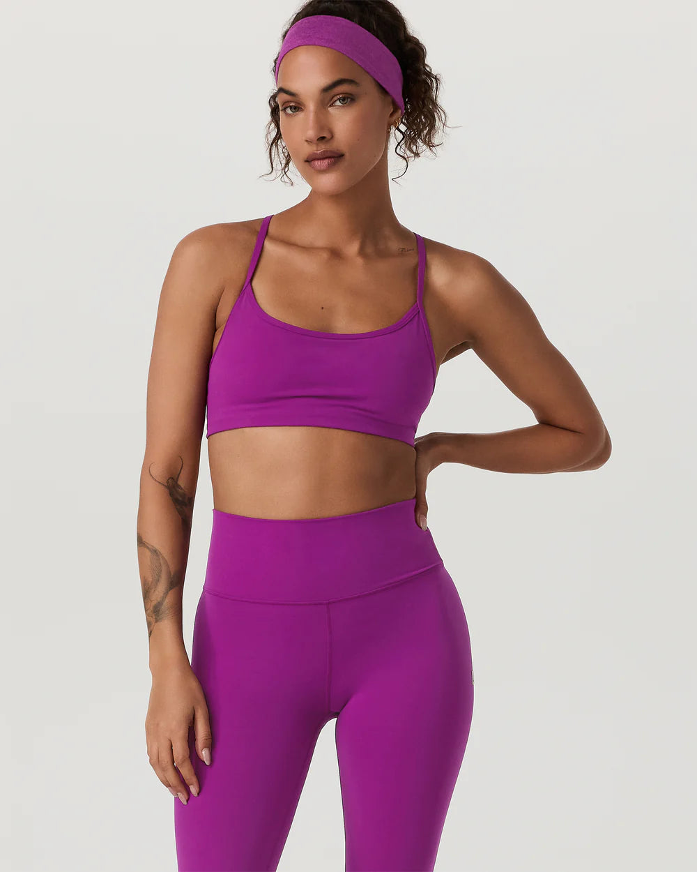 Woman wearing a purple sports bra and leggings on a white background
