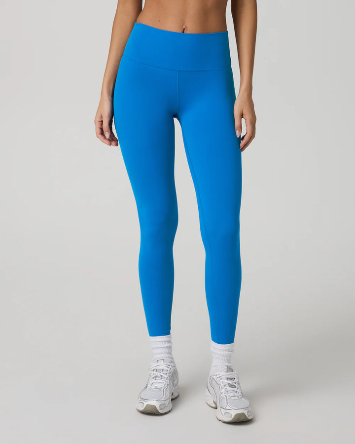 Person wearing bright blue leggings on a plain background