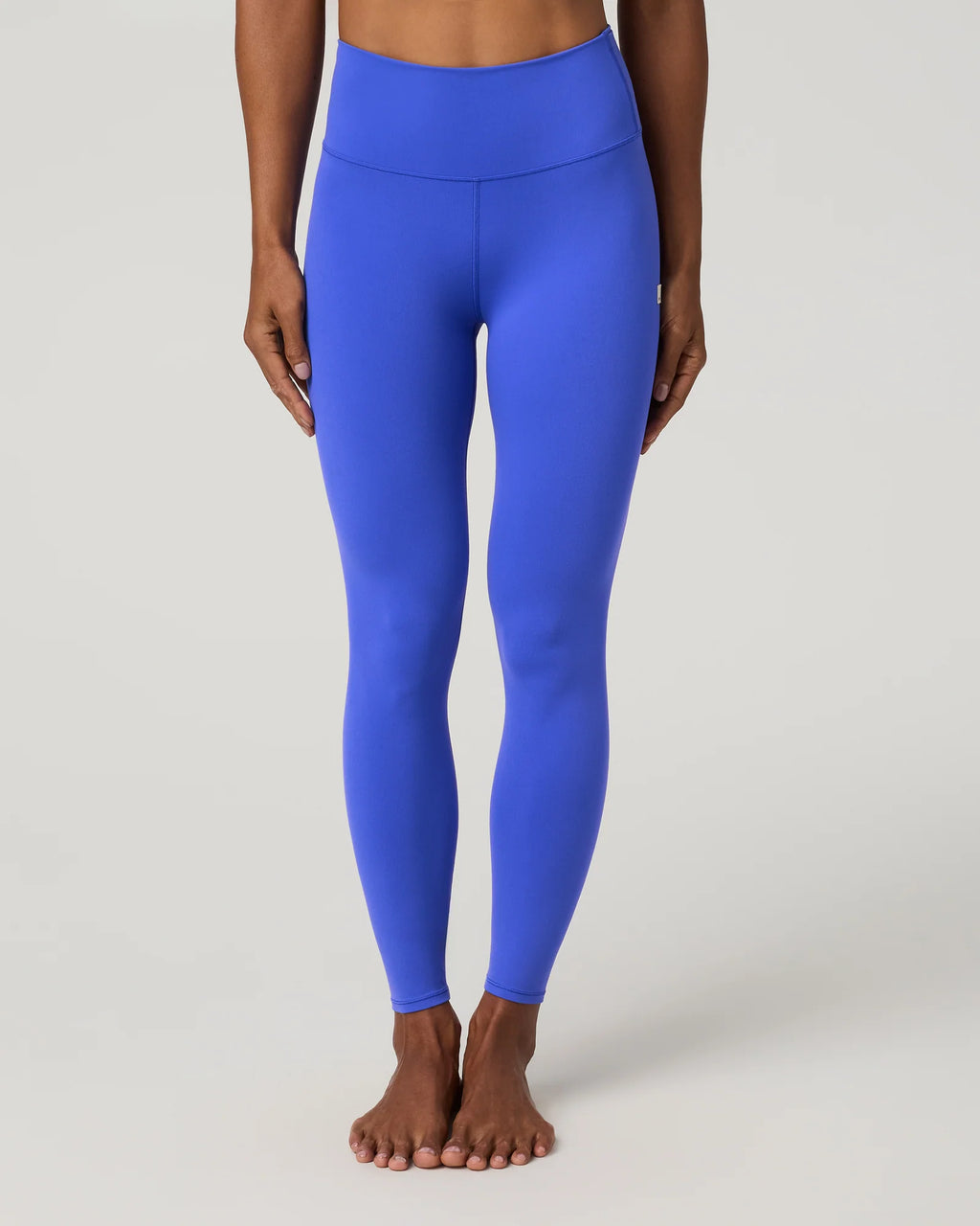 A model wearing bright royal blue high-waisted leggings, shown from the waist down against a light gray studio background.