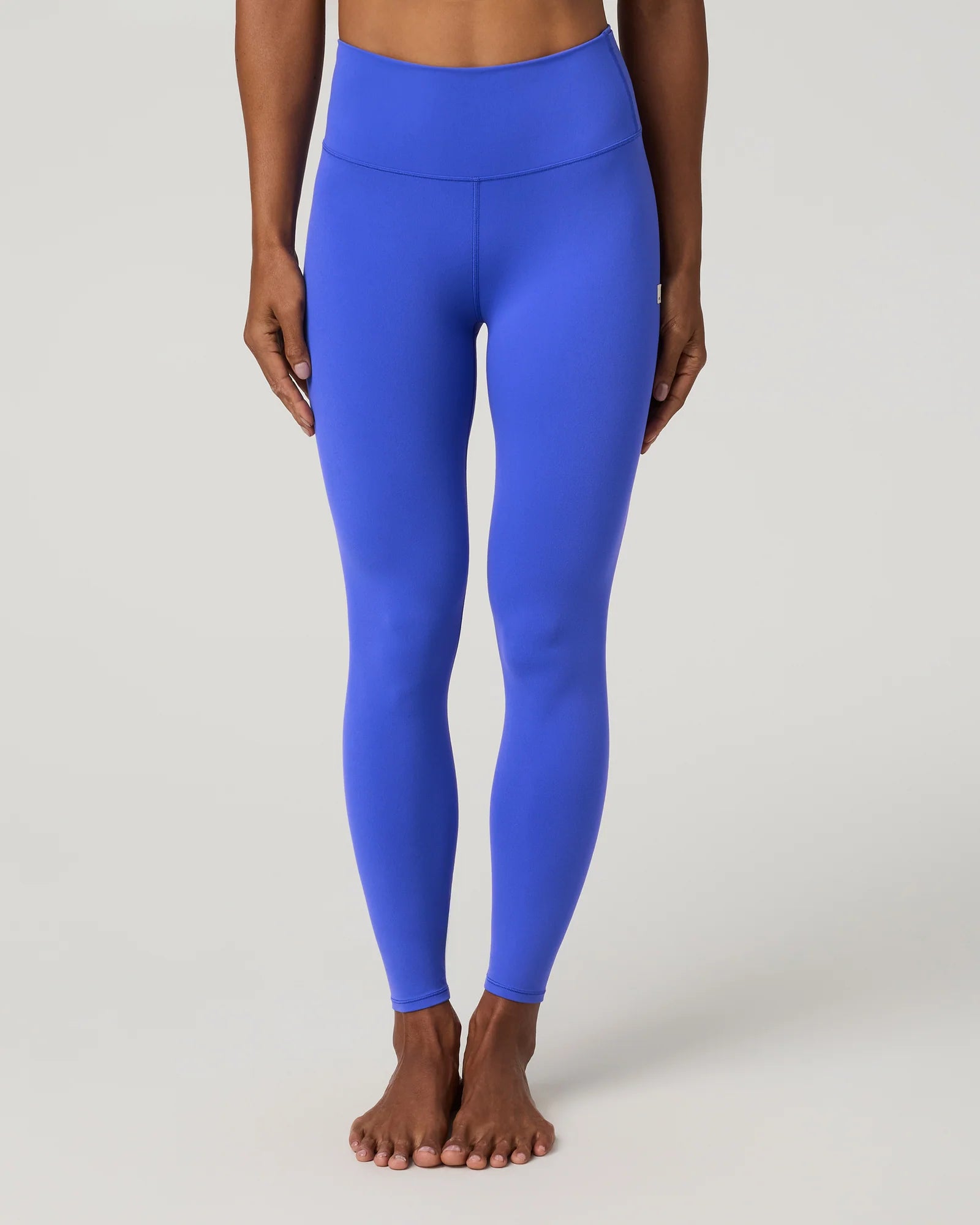 A model wearing bright royal blue high-waisted leggings, shown from the waist down against a light gray studio background.