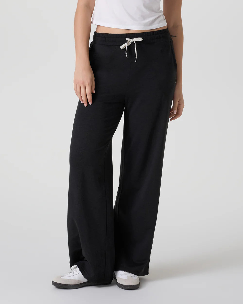 Person wearing black wide-leg pants with a white top on a light gray background