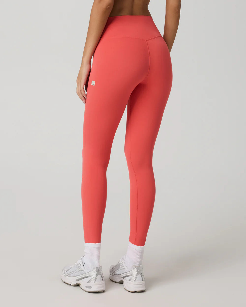 Person wearing coral leggings on a plain background