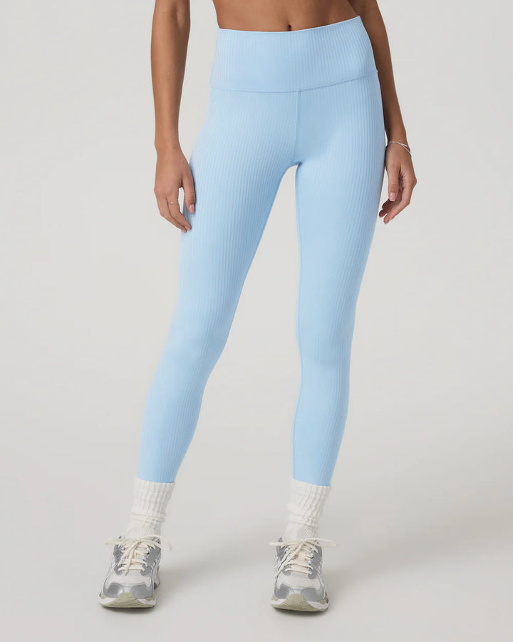 Person wearing light blue leggings on a plain background