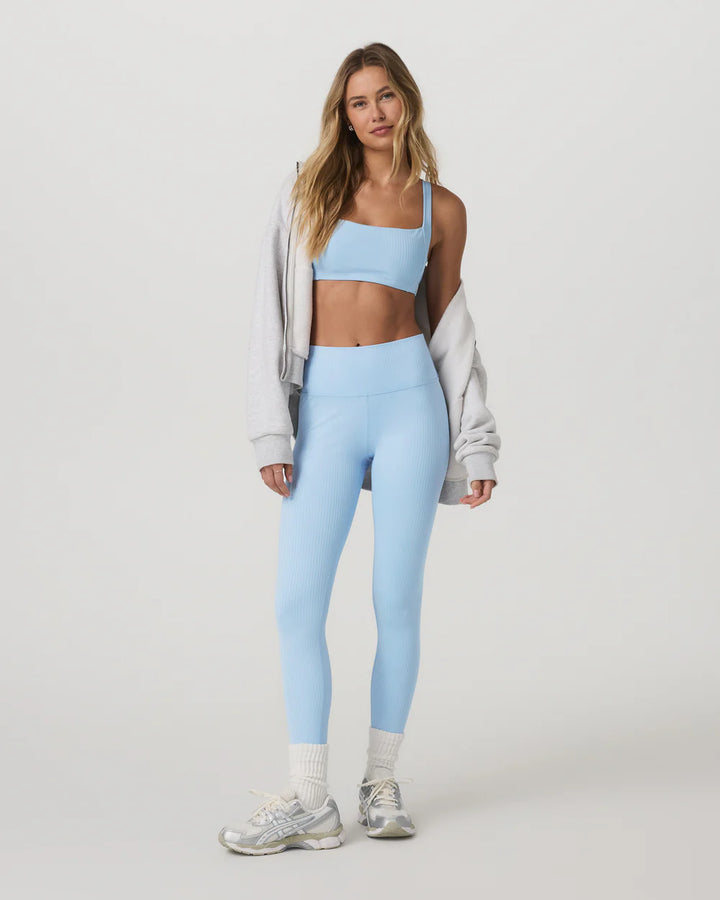 Woman wearing a light blue athletic outfit on a white background