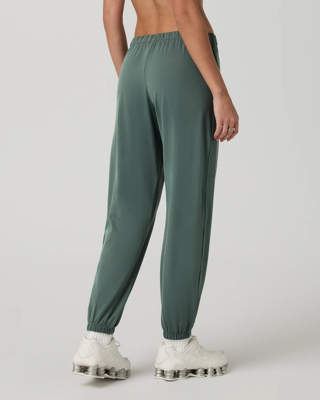 Green jogger pants worn by a person on a white background