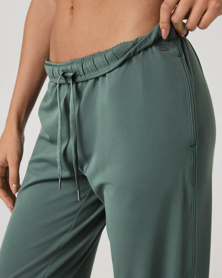 Green jogger pants being worn by a person on a plain background
