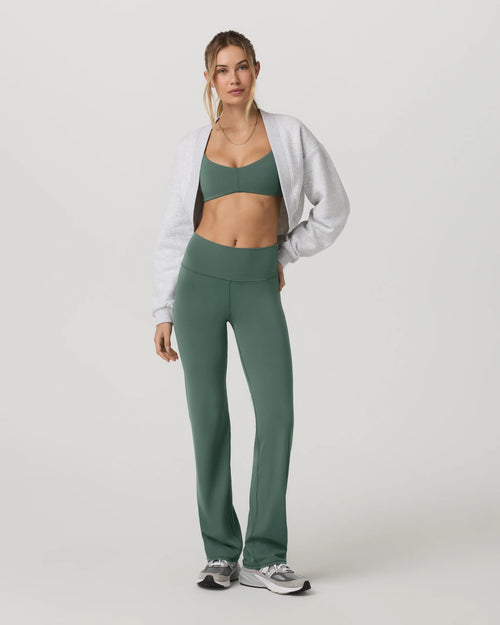 Woman wearing a green athletic outfit with a white jacket on a white background