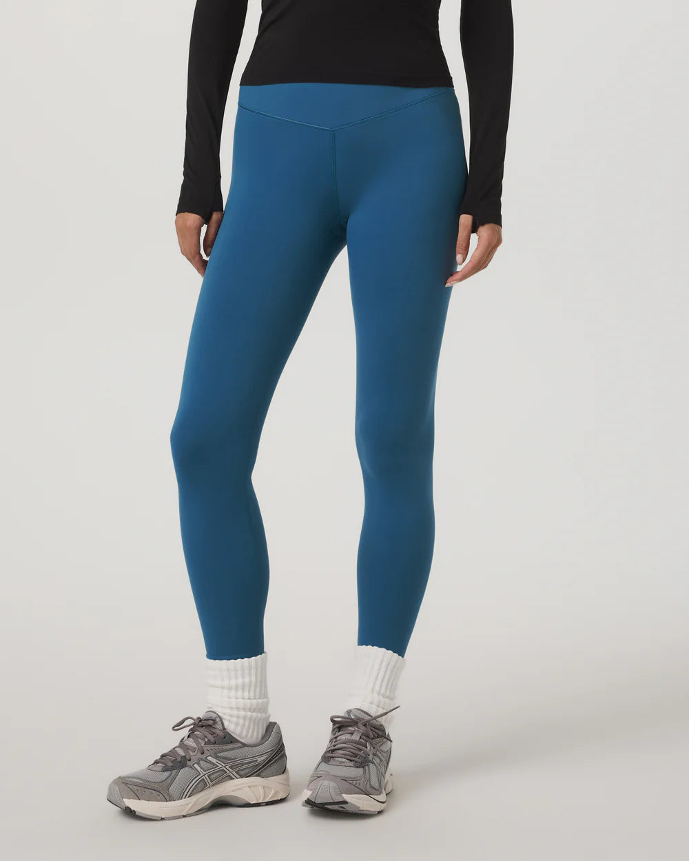 Person wearing blue leggings and black long-sleeve top on a white background