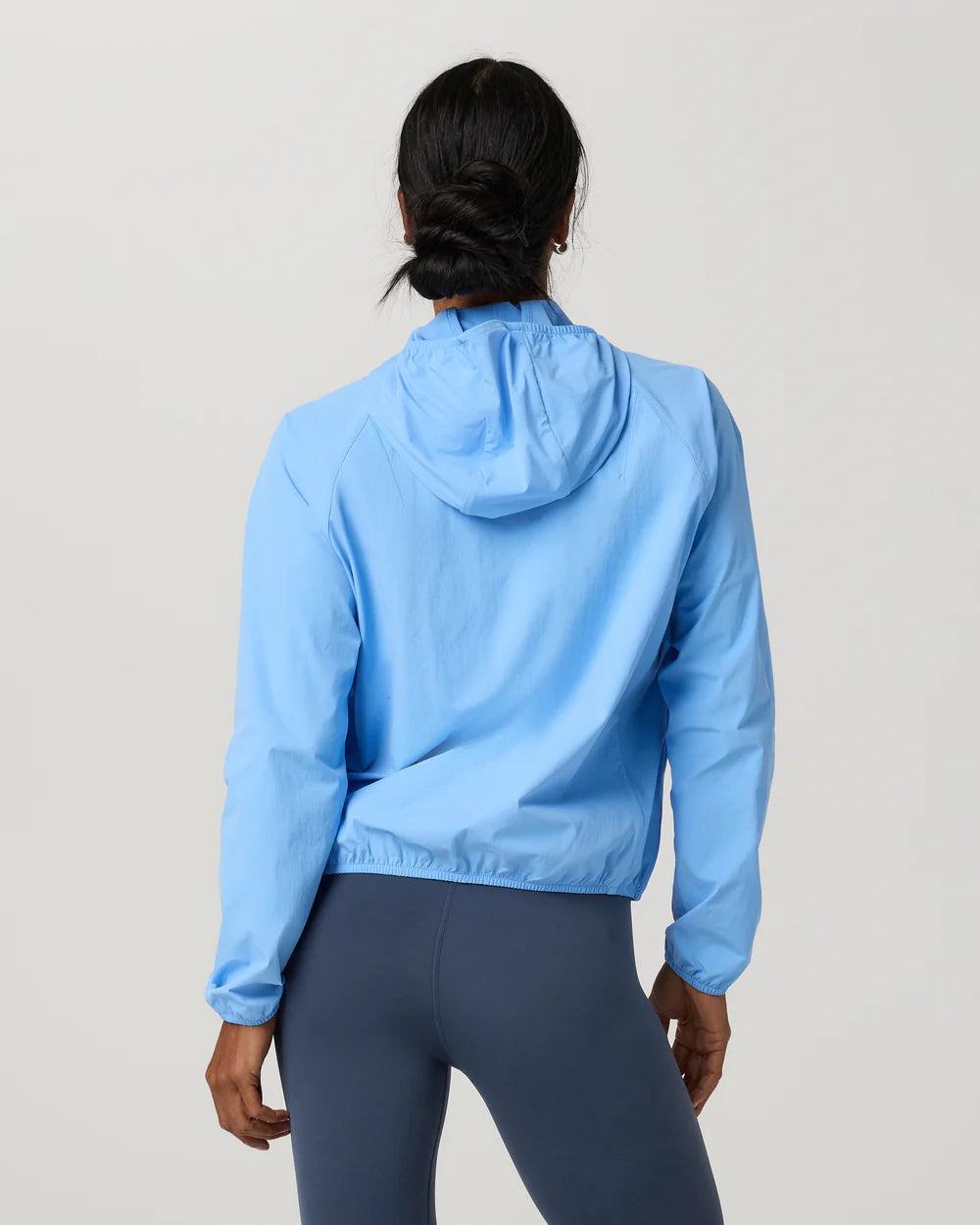 Woman wearing a light blue jacket and dark blue leggings on a gray 
