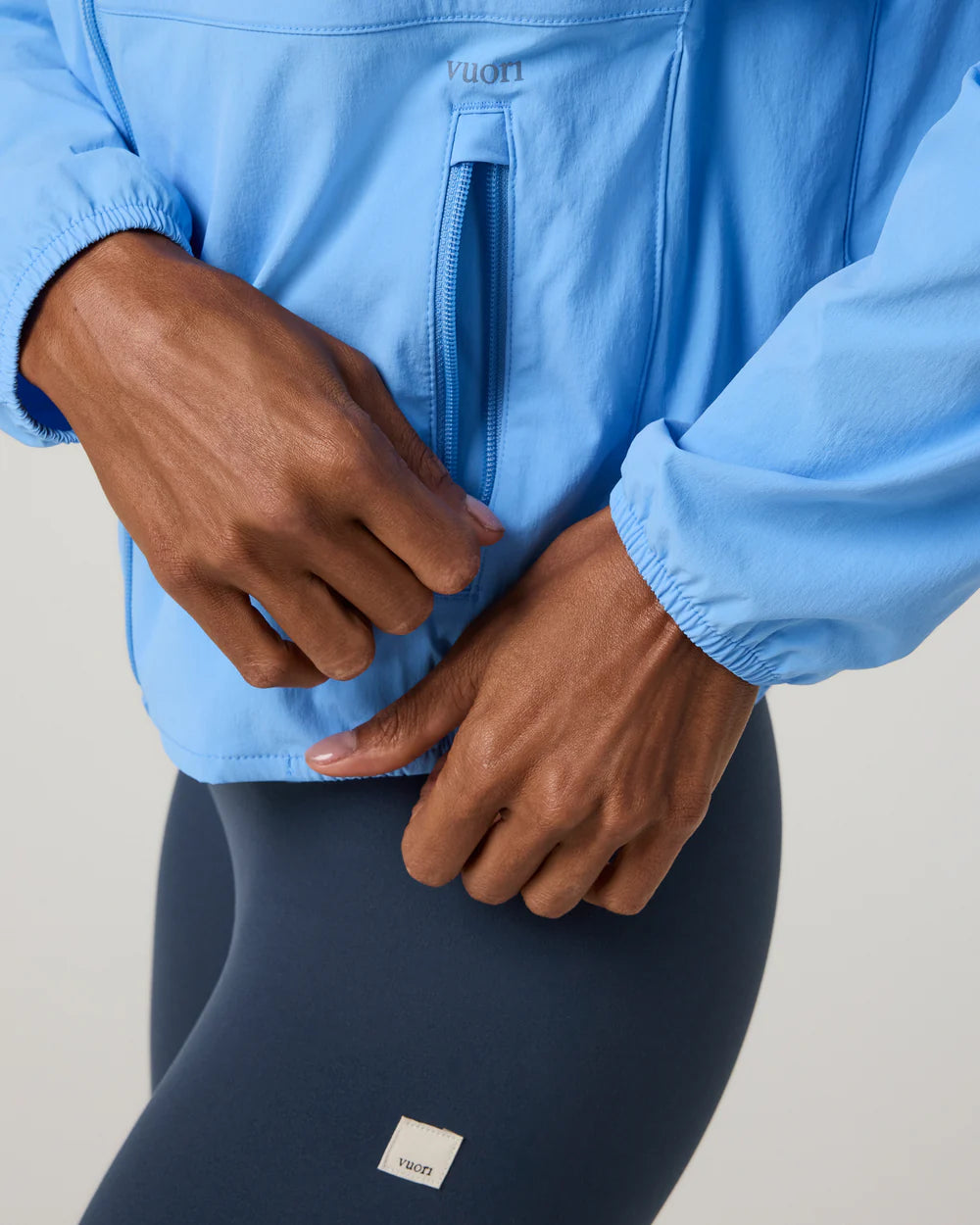 Person wearing a blue jacket and navy pants with a visible brand logo on a neutral background