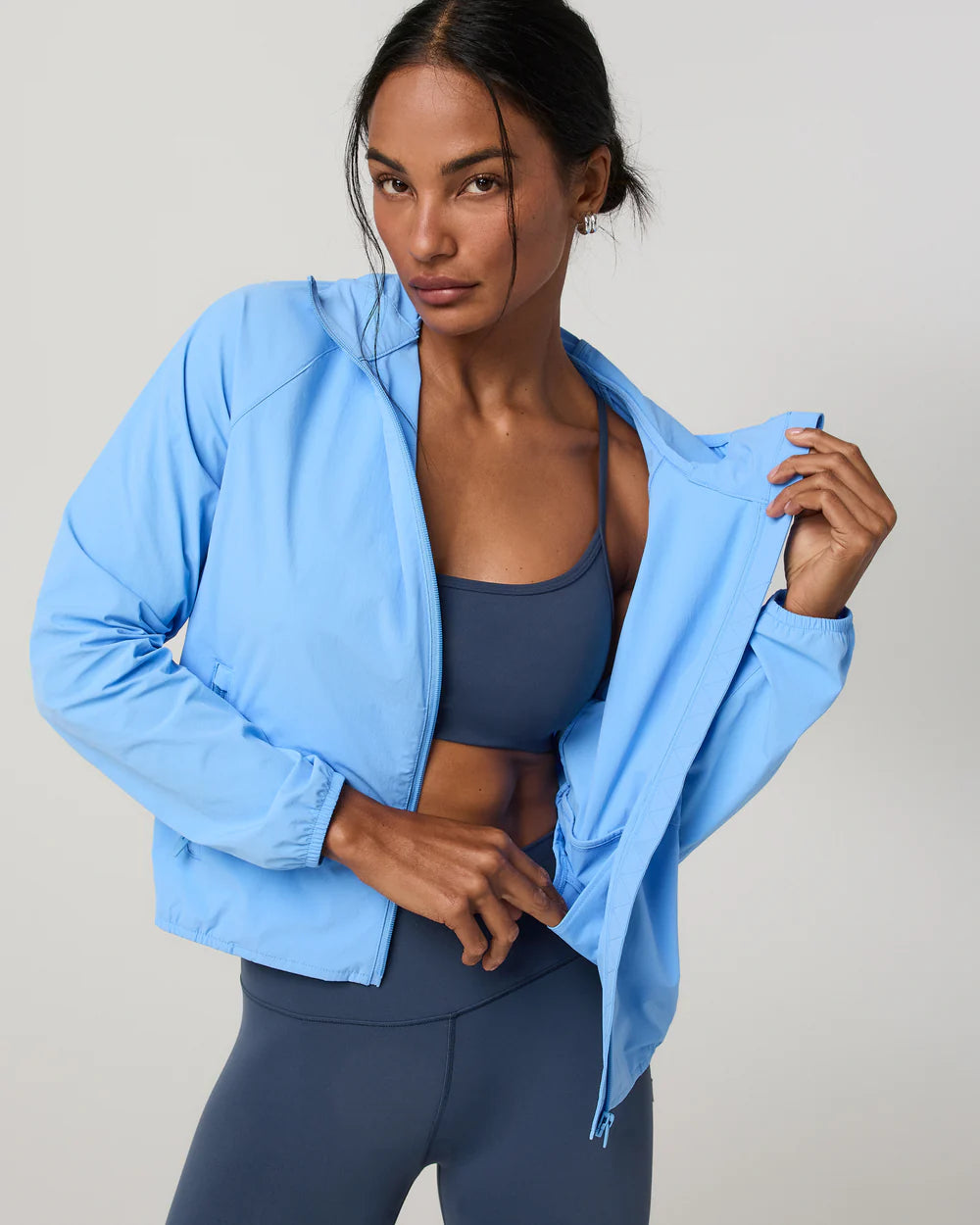 Woman wearing a light blue jacket and dark blue leggings on a gray 
