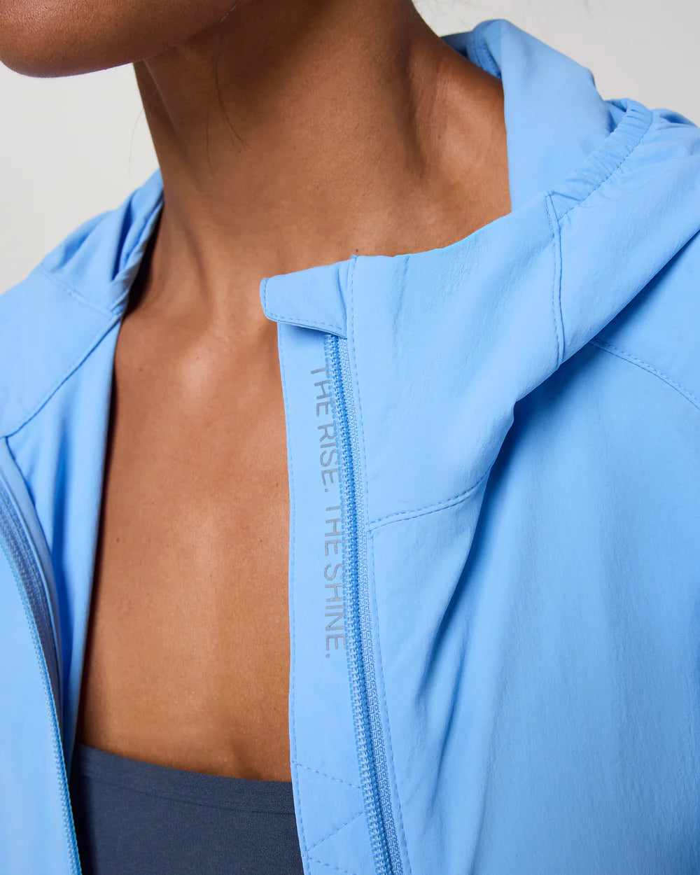 Close-up of a person wearing a light blue jacket with a visible brand logo.