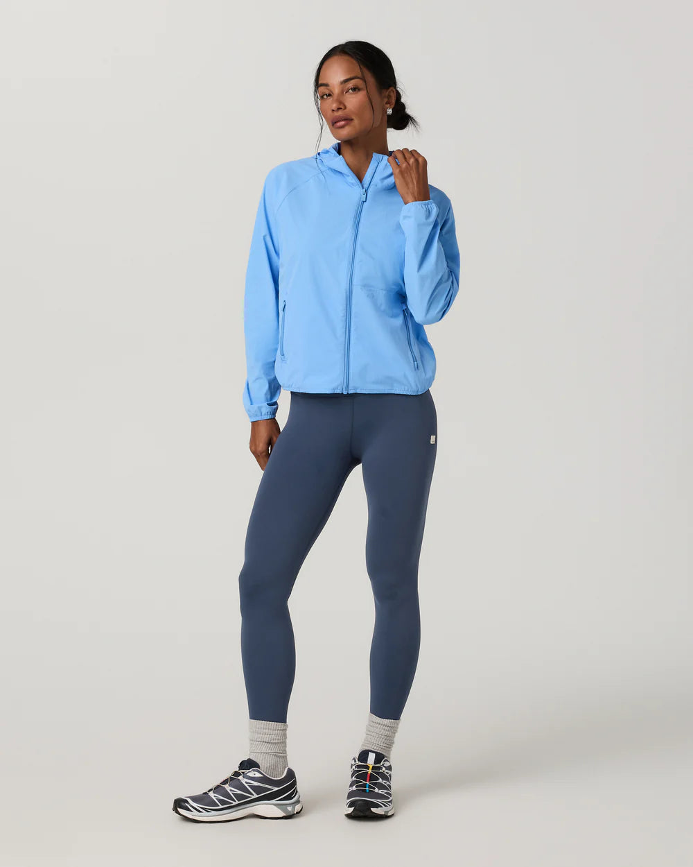 Woman wearing a light blue jacket and dark blue leggings on a white background
