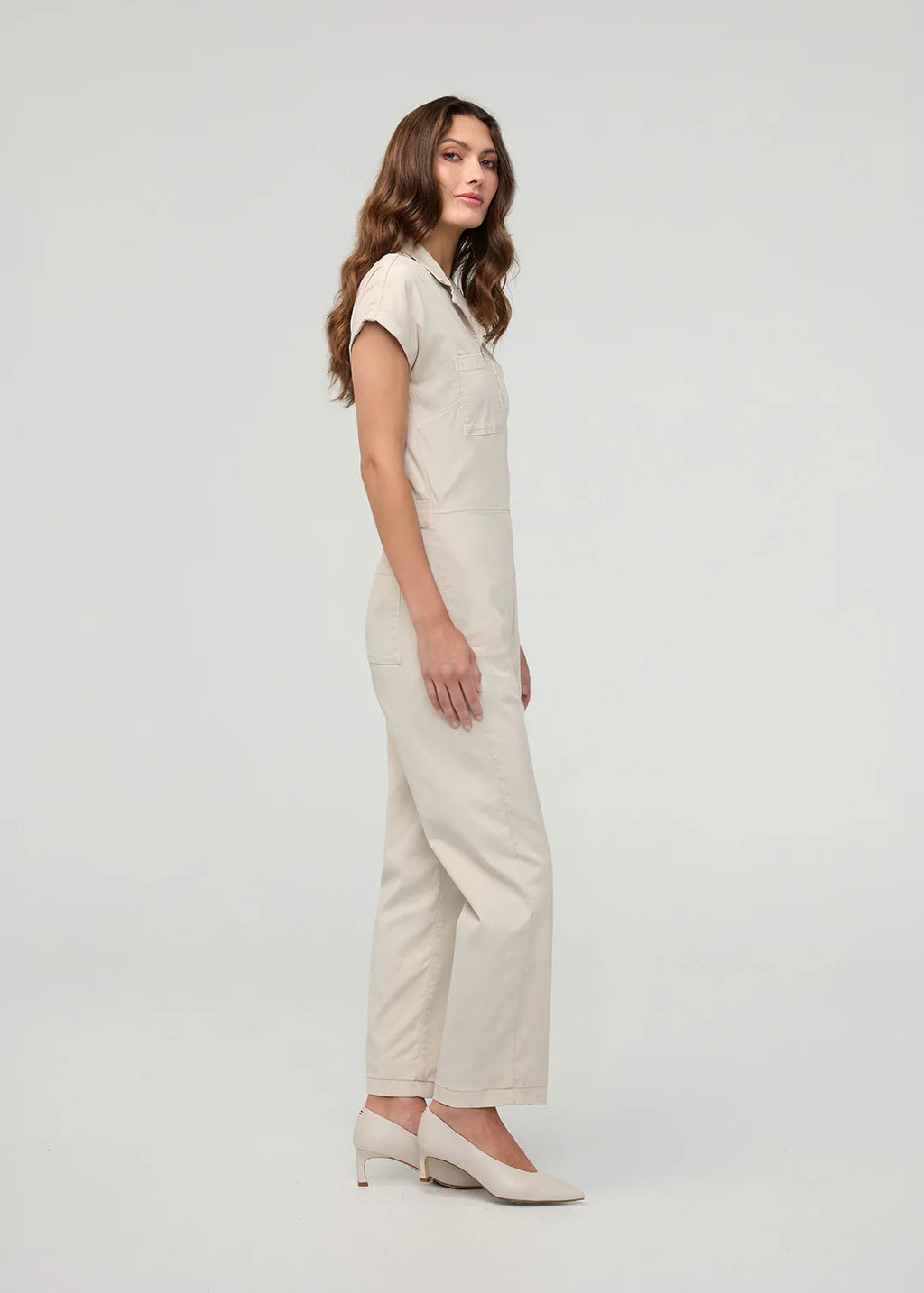 Woman wearing a beige jumpsuit on a white background