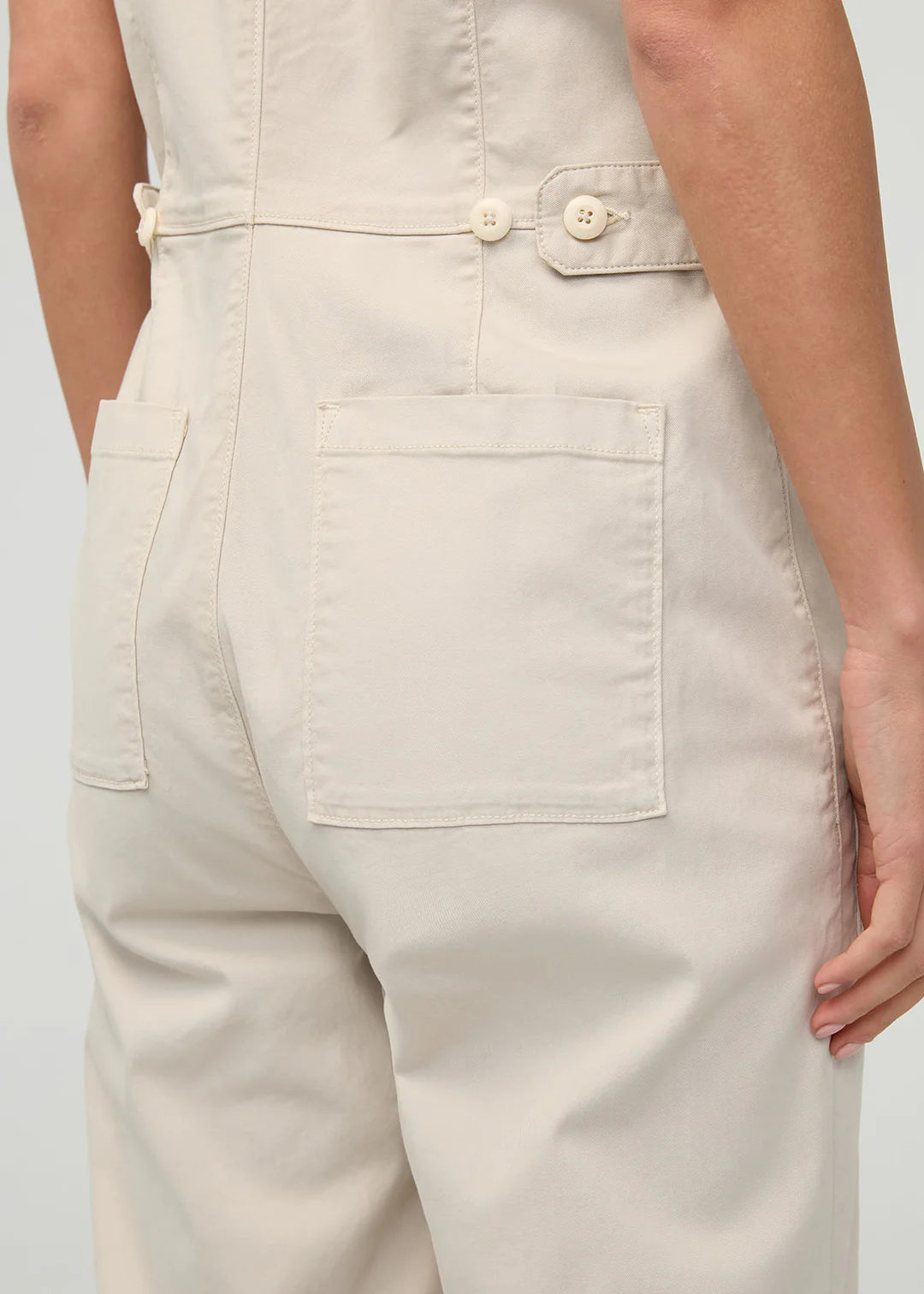 Beige overalls worn by a person on a plain background