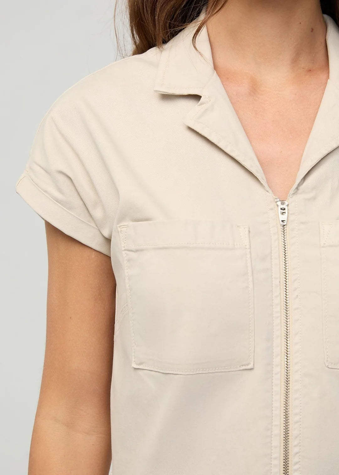 Beige sleeveless jacket with a zipper on a plain background